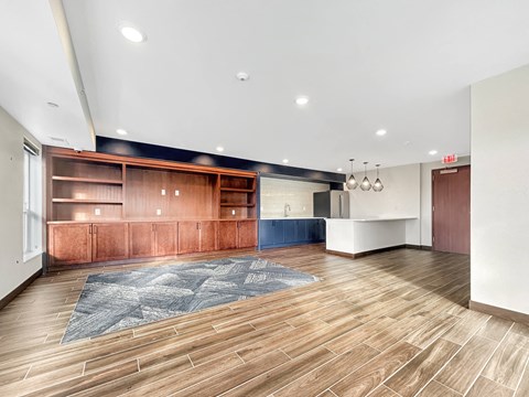 A room with wooden floors and a blue rug in the middle.