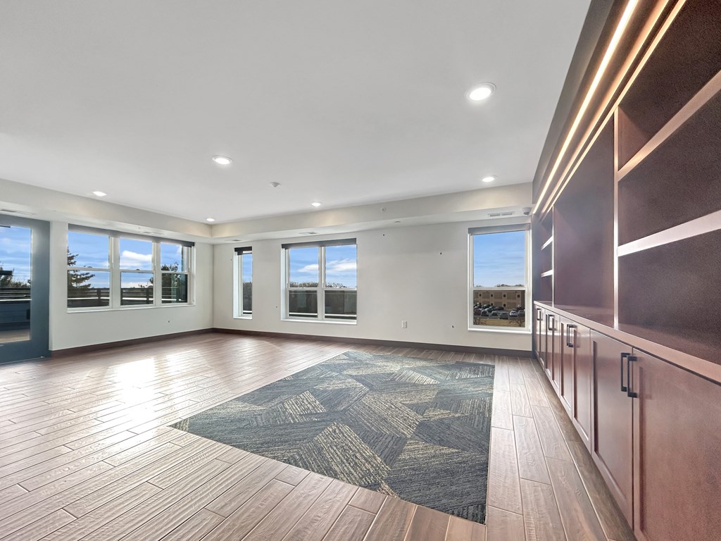 an empty living room with wood flooring and large windows