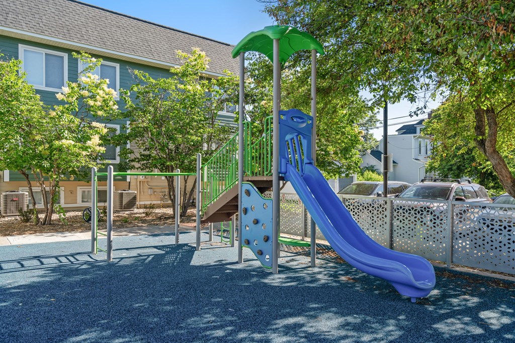 a playground with a blue slide and a green umbrella