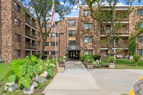 exterior view of an apartment building with a sidewalk and an flag
