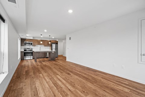 a living room and kitchen with wood floors and white walls