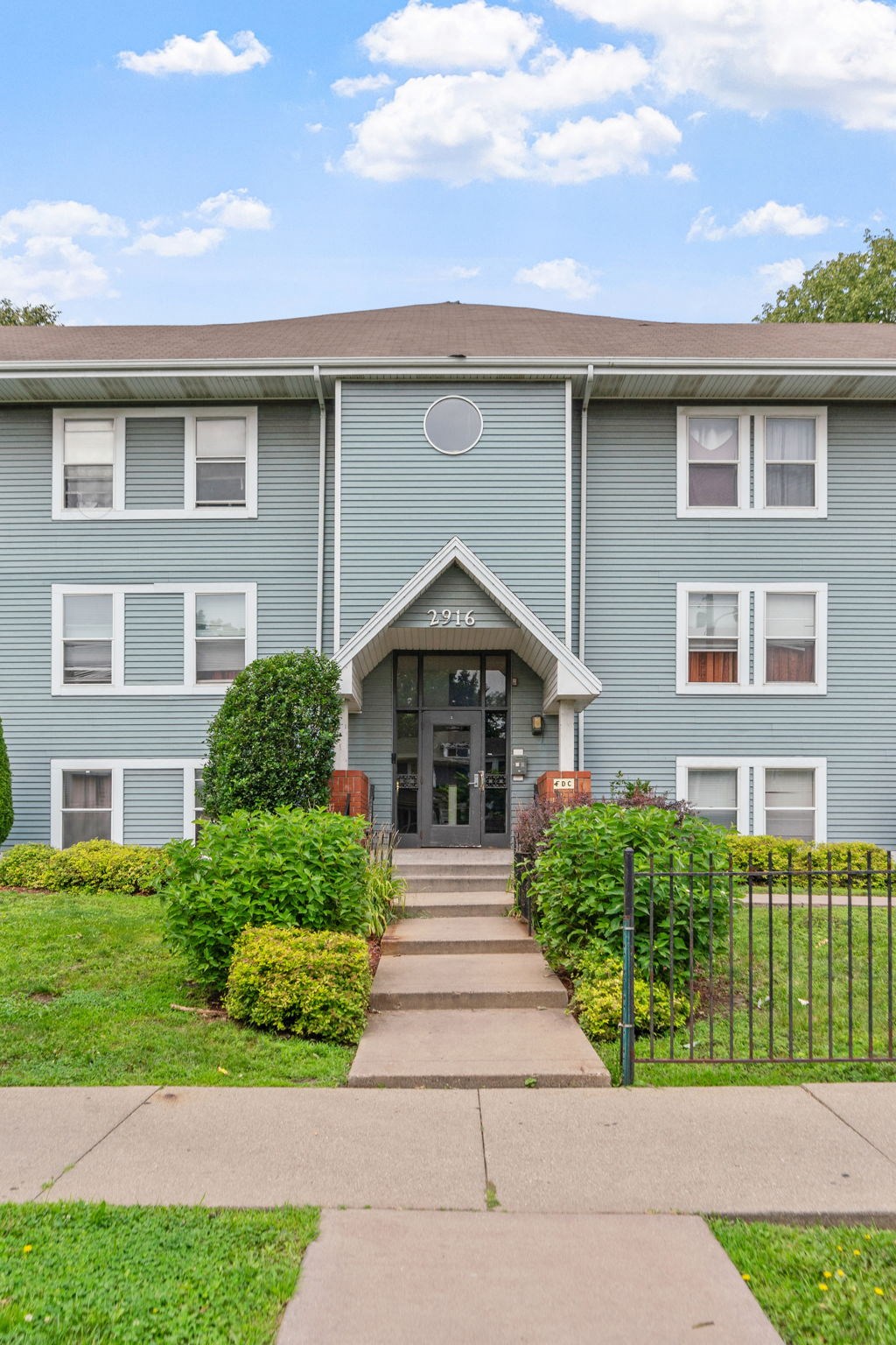 the front of a blue house with a sidewalk in front of it
