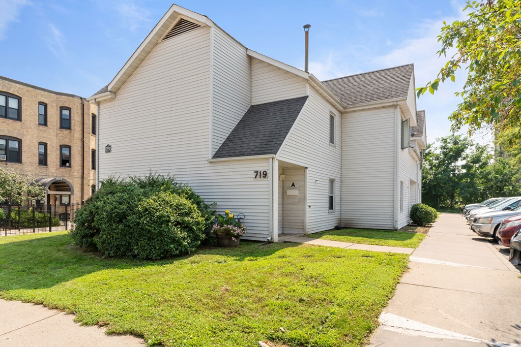 a white house with a sidewalk and a brick building