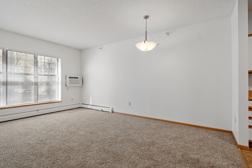 view of living room with large windows, hanging ceiling lamp and wall mounted air conditioner