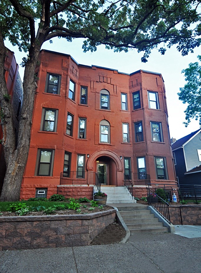 a red brick building with stairs and a tree in front