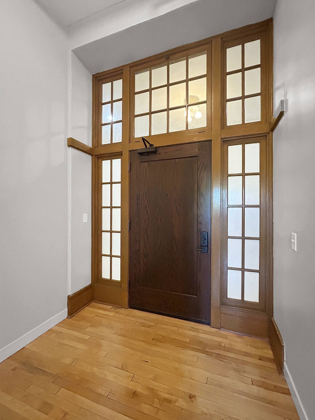the front door of a house with a hardwood floor and a window