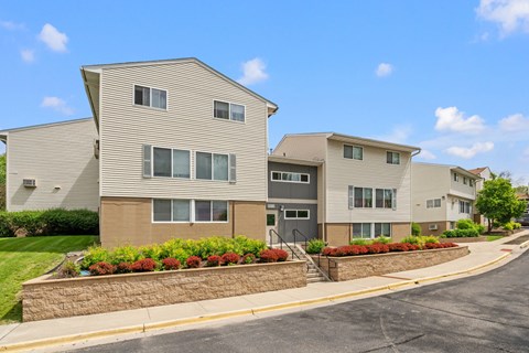 an apartment building with a stone retaining wall and flower beds