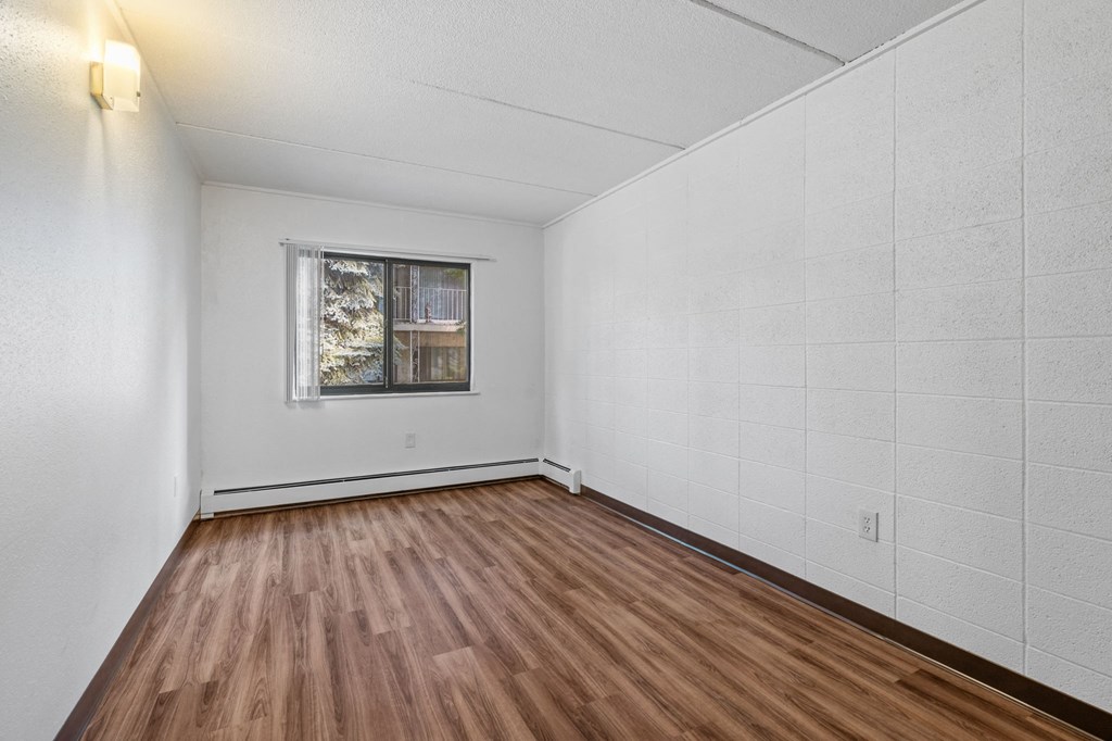 the living room has wood floors and white walls and a window