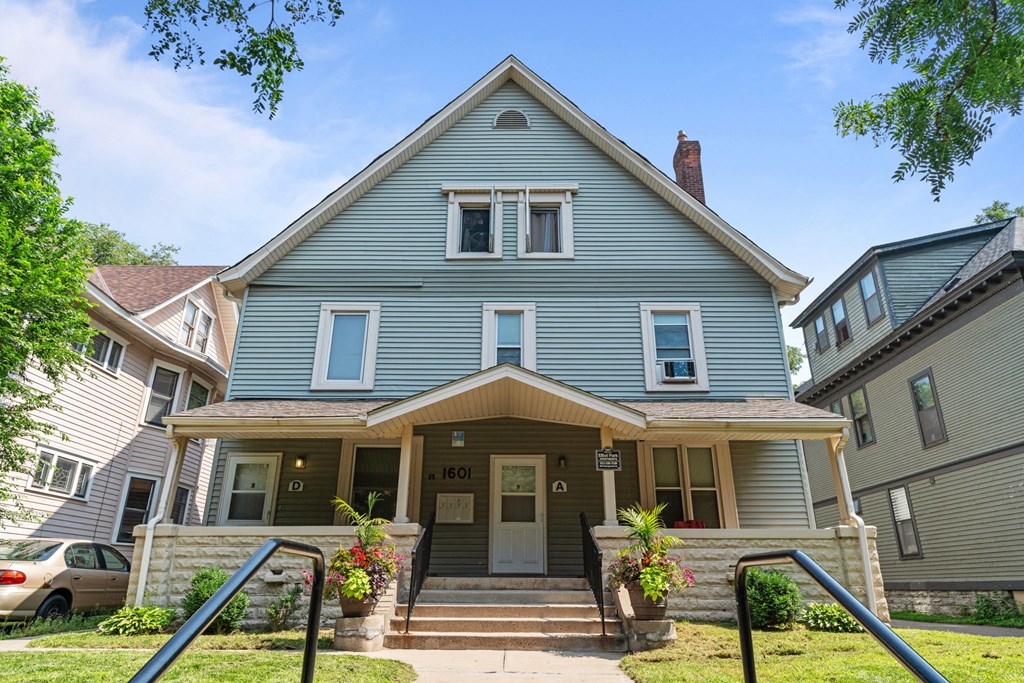 the front of a blue house with a porch and stairs