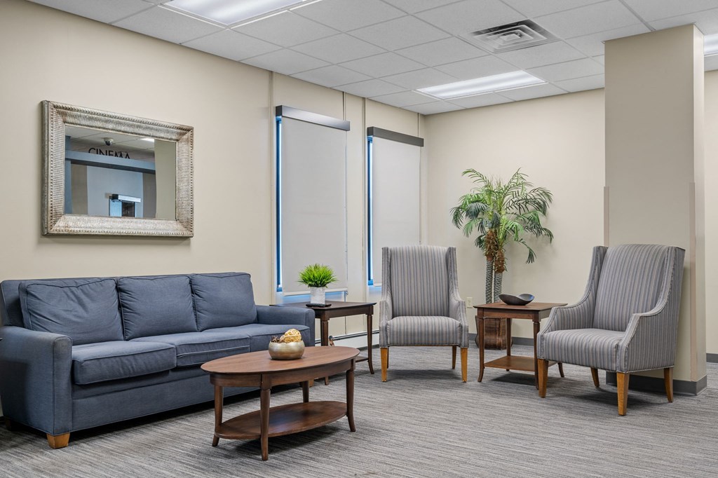 a living room with blue couches and chairs and a mirror