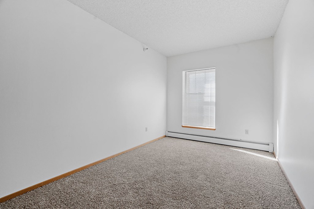 a bedroom with white walls and carpet and a window