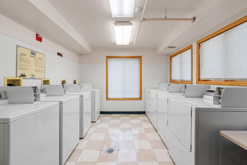a laundry room filled with white washers and dryers
