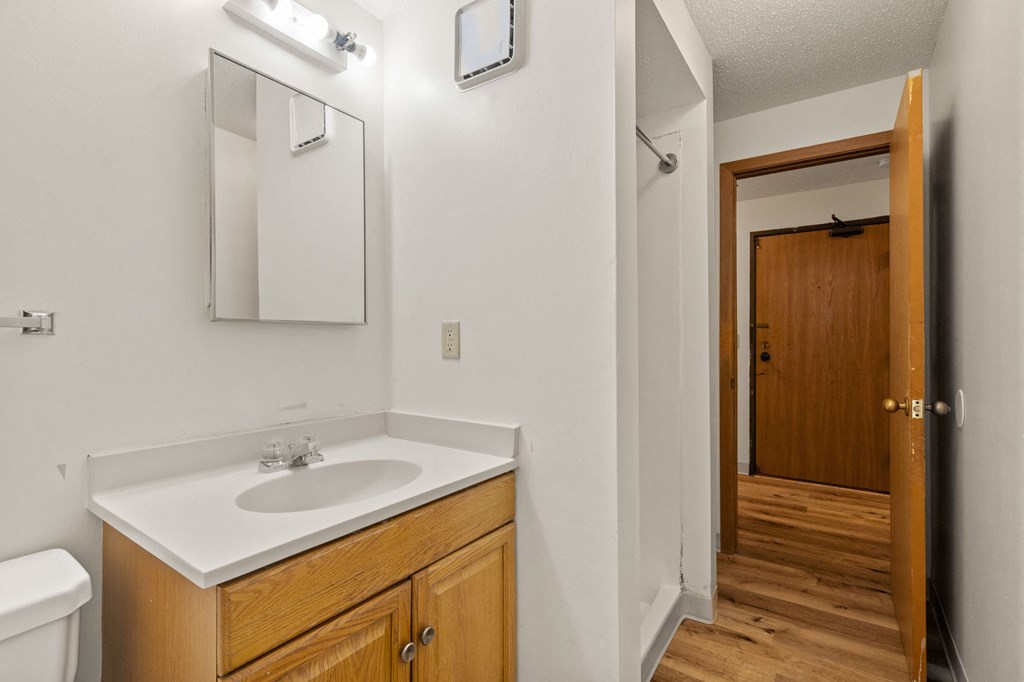 a bathroom with a sink and a mirror and a door to a hallway