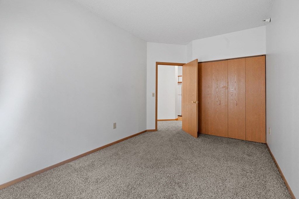 a bedroom with a door to a closet and a carpeted floor