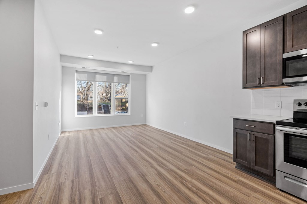 an empty kitchen and living room with wood flooring and a window
