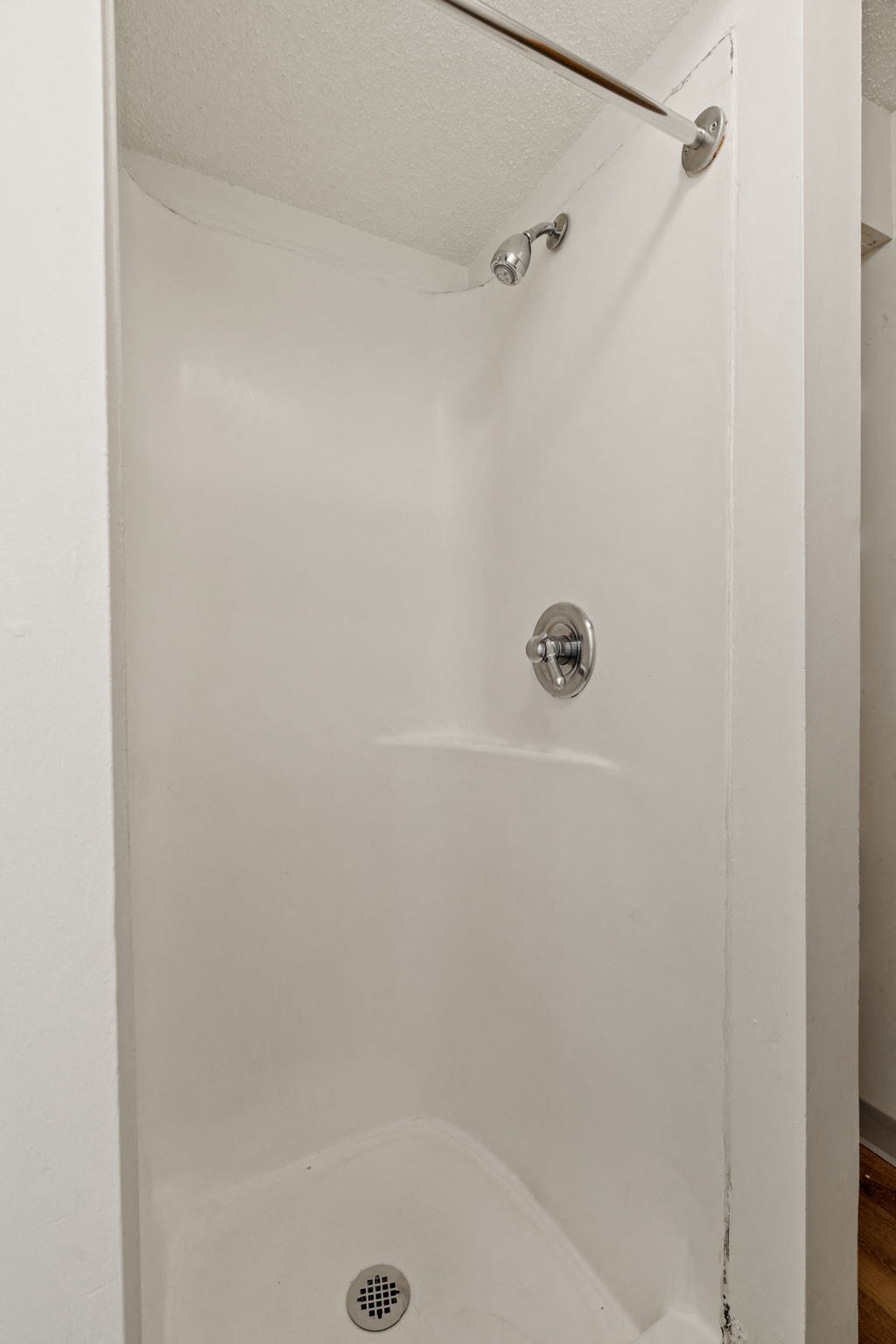 a white shower in a bathroom with the door open