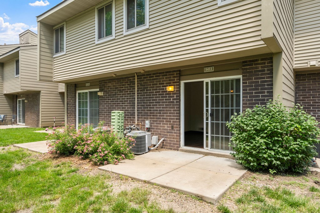 the front of a brick house with a patio and a backdoor