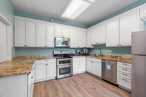 a kitchen with white cabinets and marble counter tops