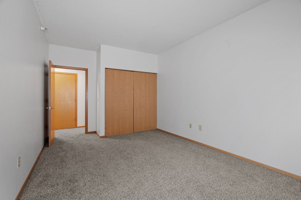 a bedroom with carpet and a door to a closet