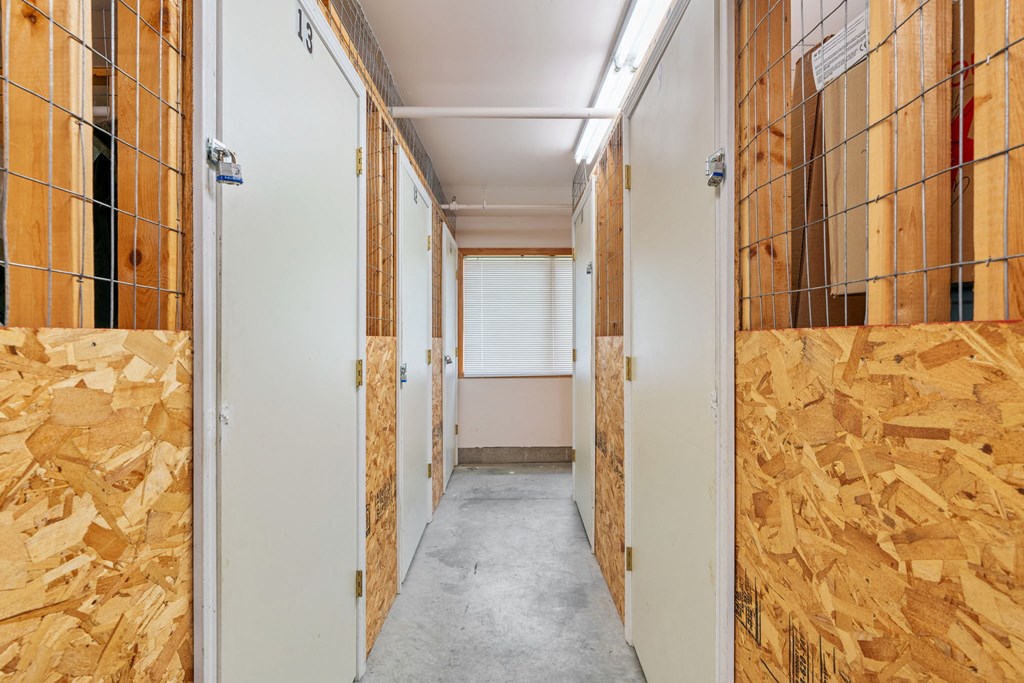 a room with plywood on the walls and a hallway with doors and a window