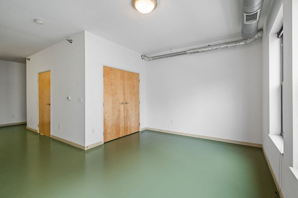 an empty room with white walls and green floor and a wooden door