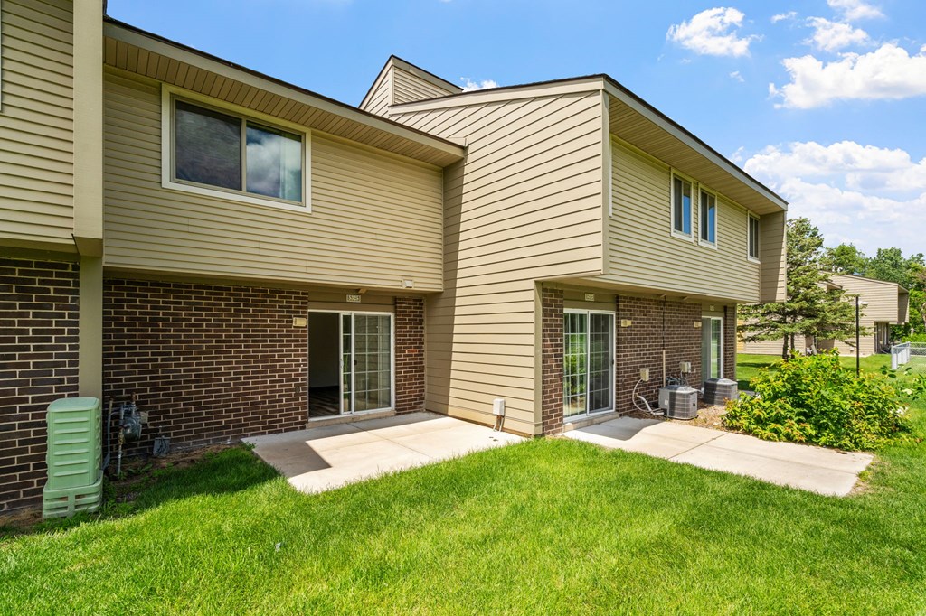 a tan and brick house with a patio and grass