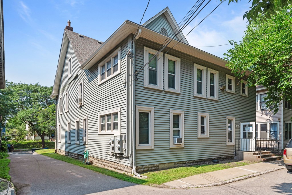 a gray house with white siding on the corner of a street