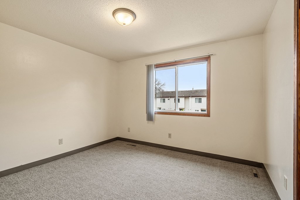 A room with a window and carpeted floor.