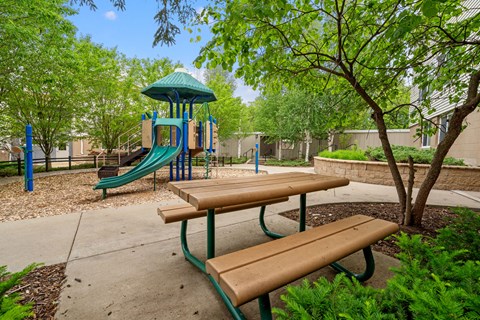 a playground with a slide and benches in a park