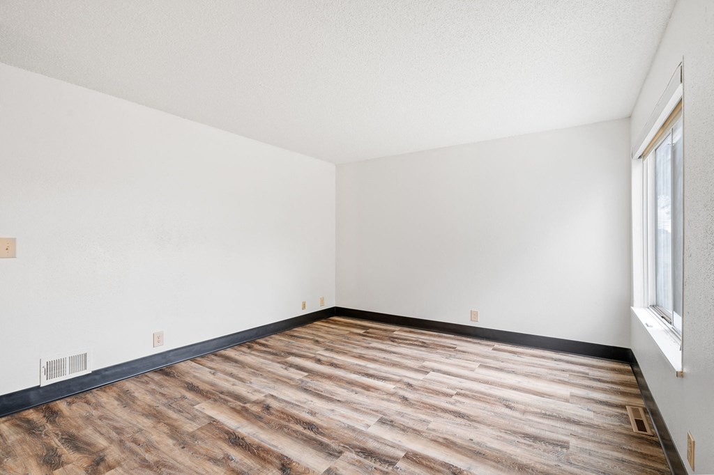 an empty room with wood flooring and a window