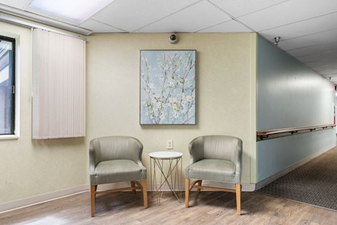 two chairs in a room with a table and a painting on the wall