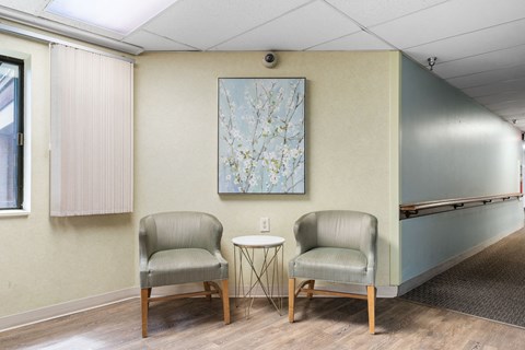 two chairs in a room with a table and a painting on the wall