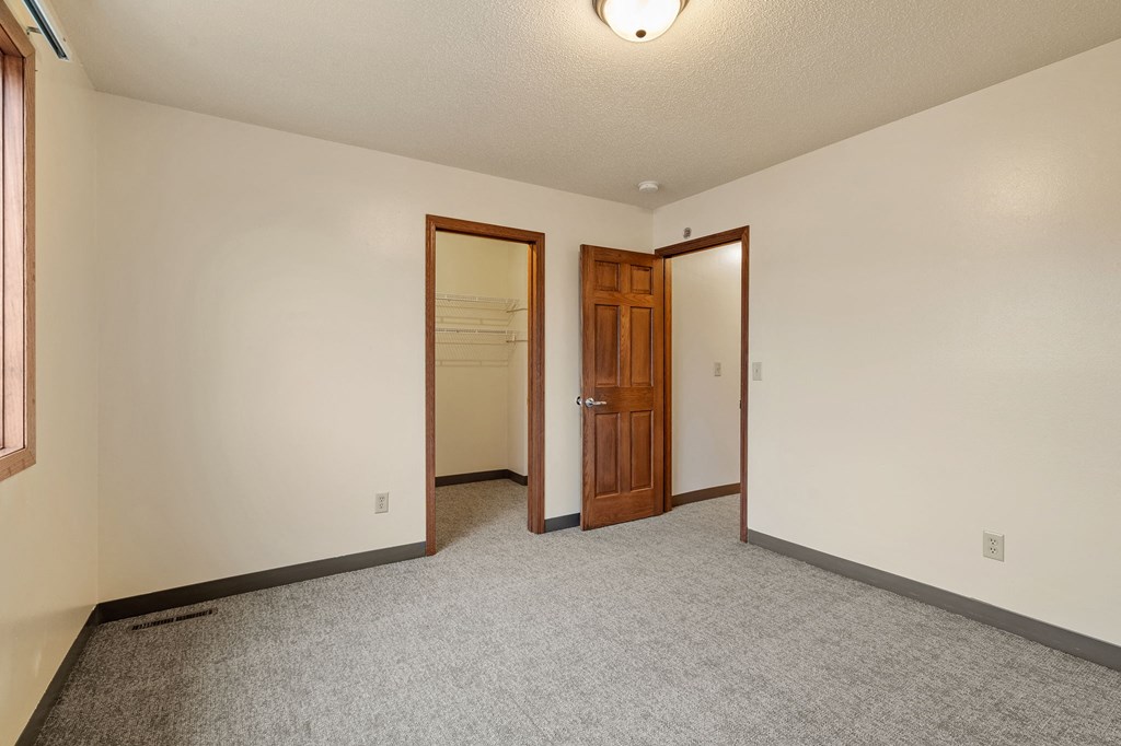 A room with a carpeted floor and a wooden door.