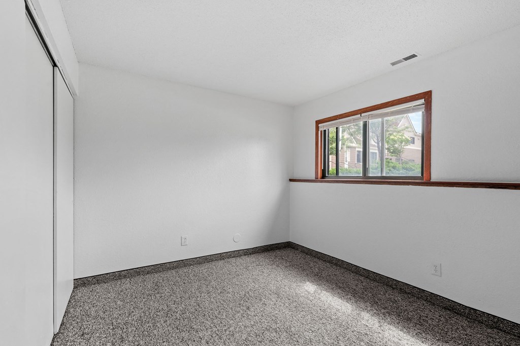 the living room of a house with white walls and a window