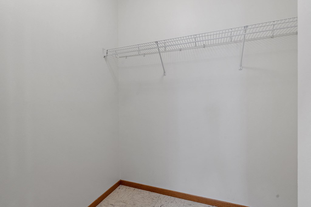 an empty room with a white wall and a wire rack on the ceiling