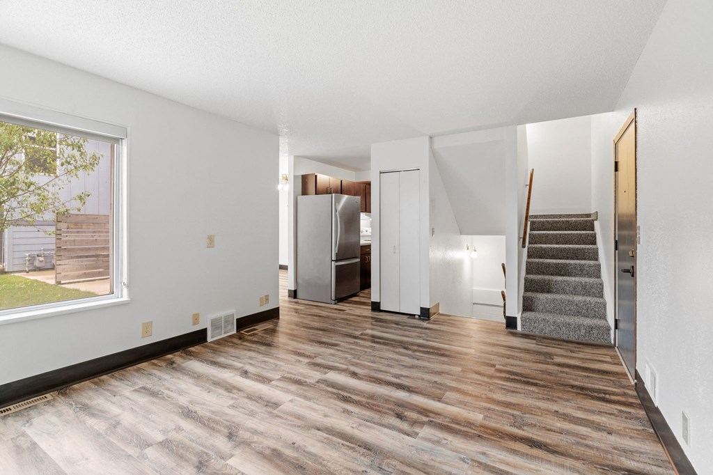 an empty living room with hardwood floors and a staircase