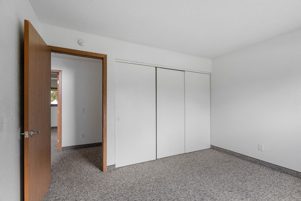 an empty room with white walls and a door to a closet