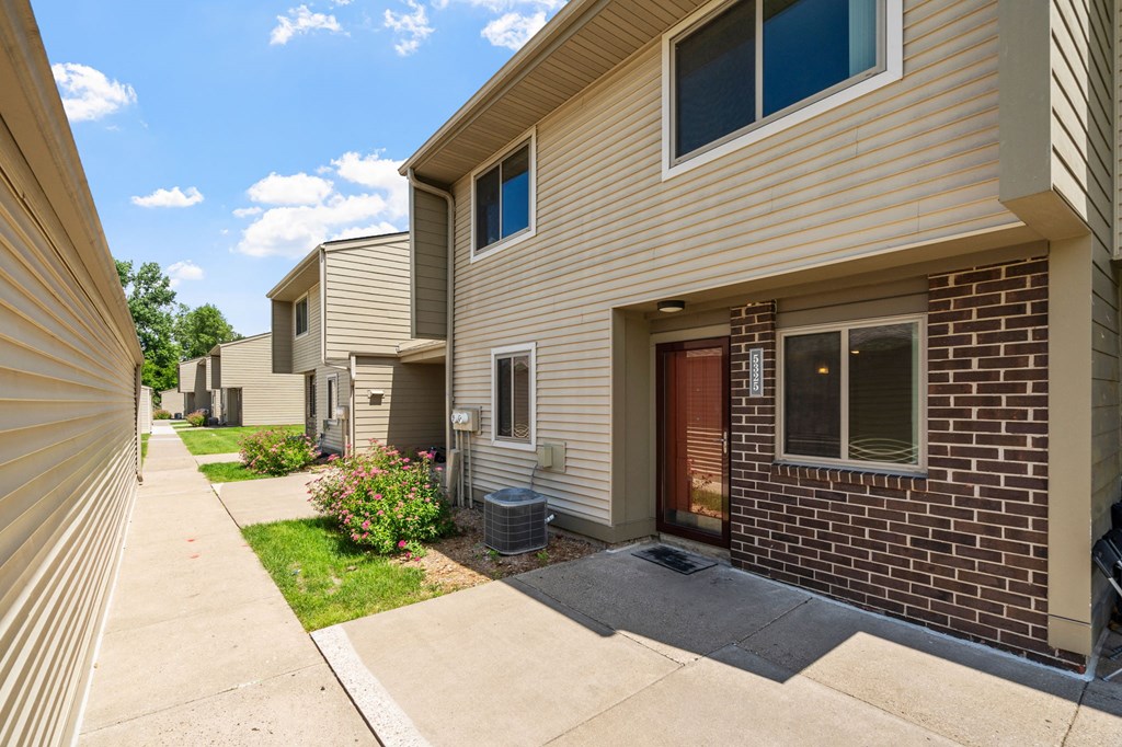 a sidewalk in front of an apartment building with a driveway