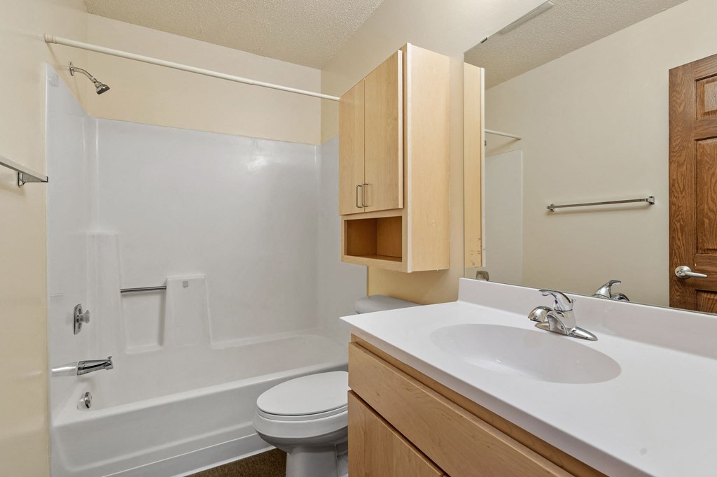 A white sink is in a bathroom with a white tub and toilet.