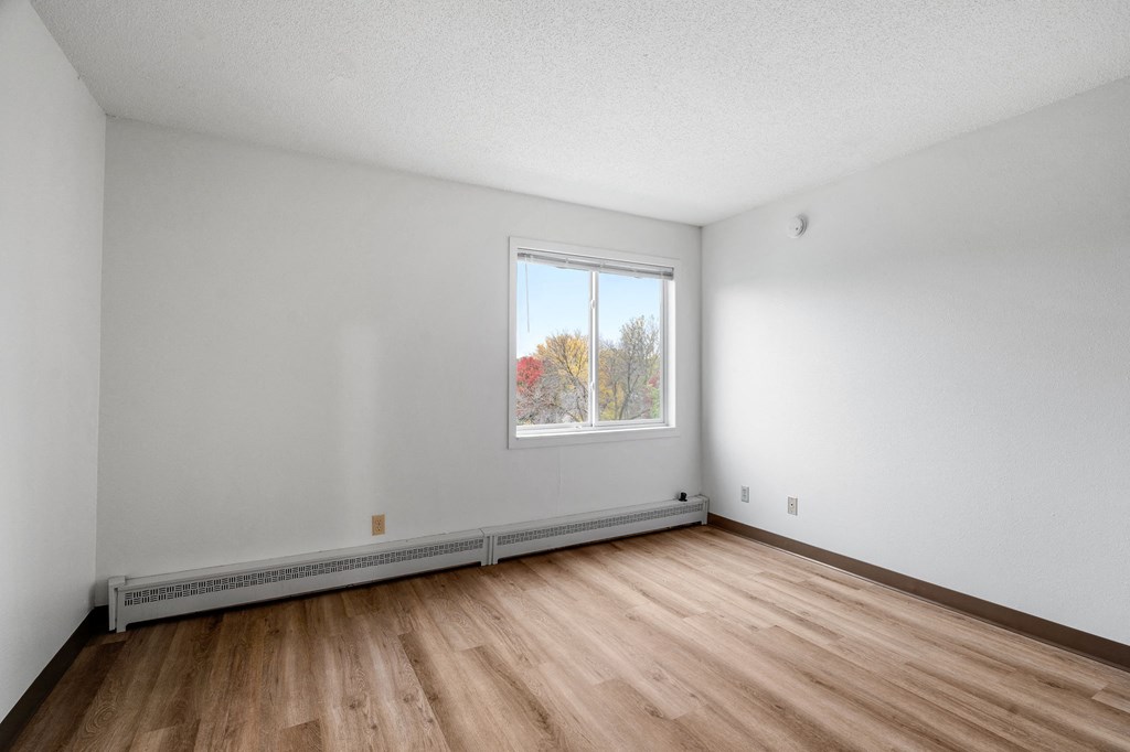 the living room of an empty house with wood floors and a window