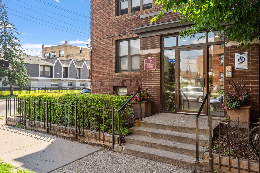 the front of a brick building with stairs and a glass door