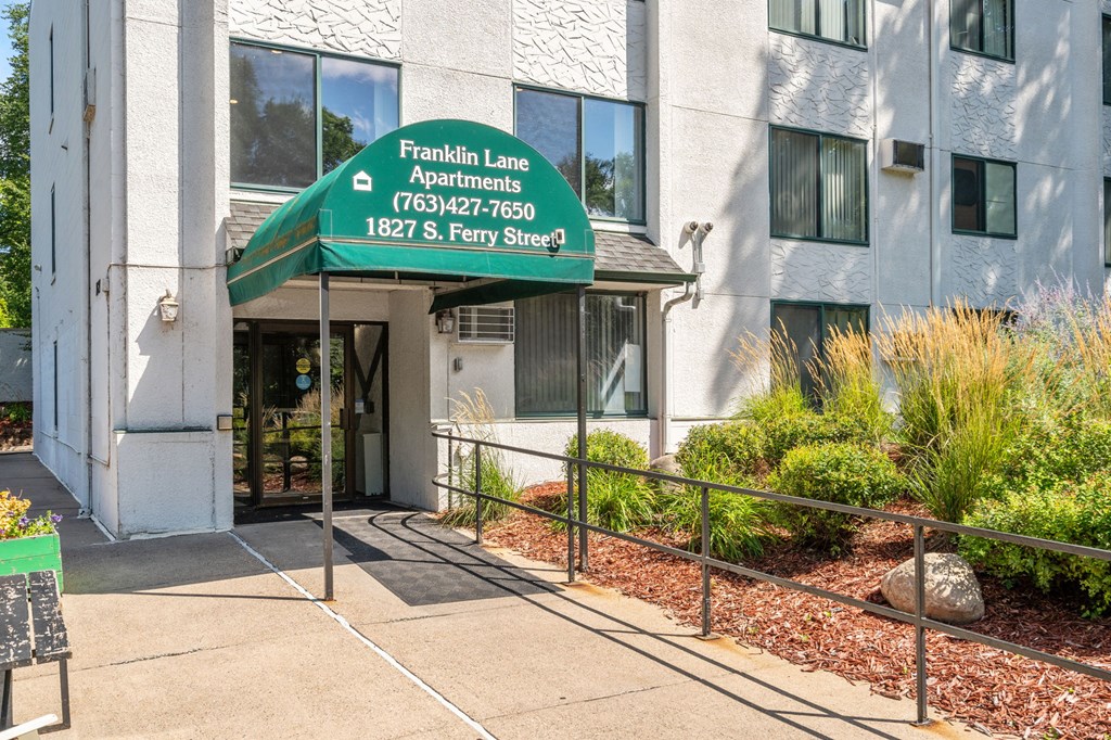the front entrance of a building with a green sign that reads