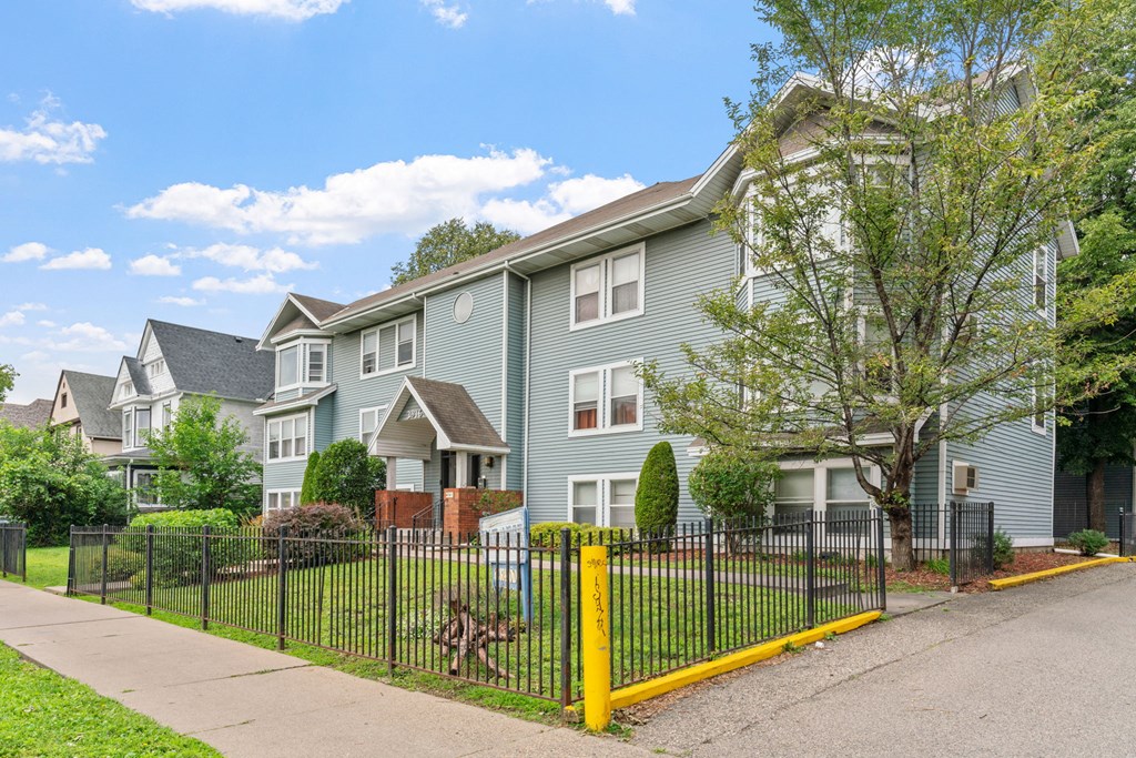 a row of houses with a fence in front of a sidewalk