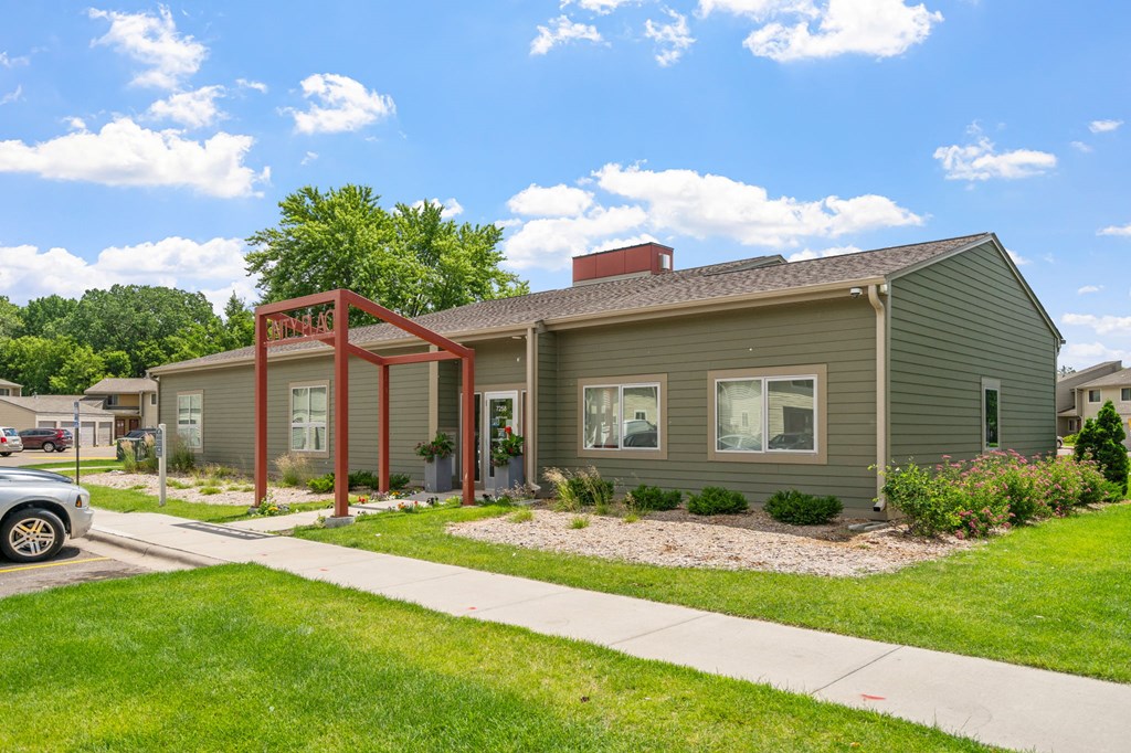 a green house with a sidewalk and lawn in front of it
