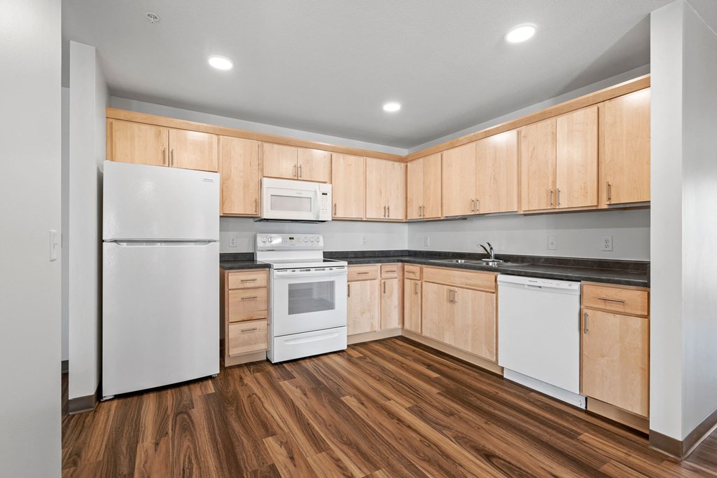 an empty kitchen with wooden cabinets and white appliances