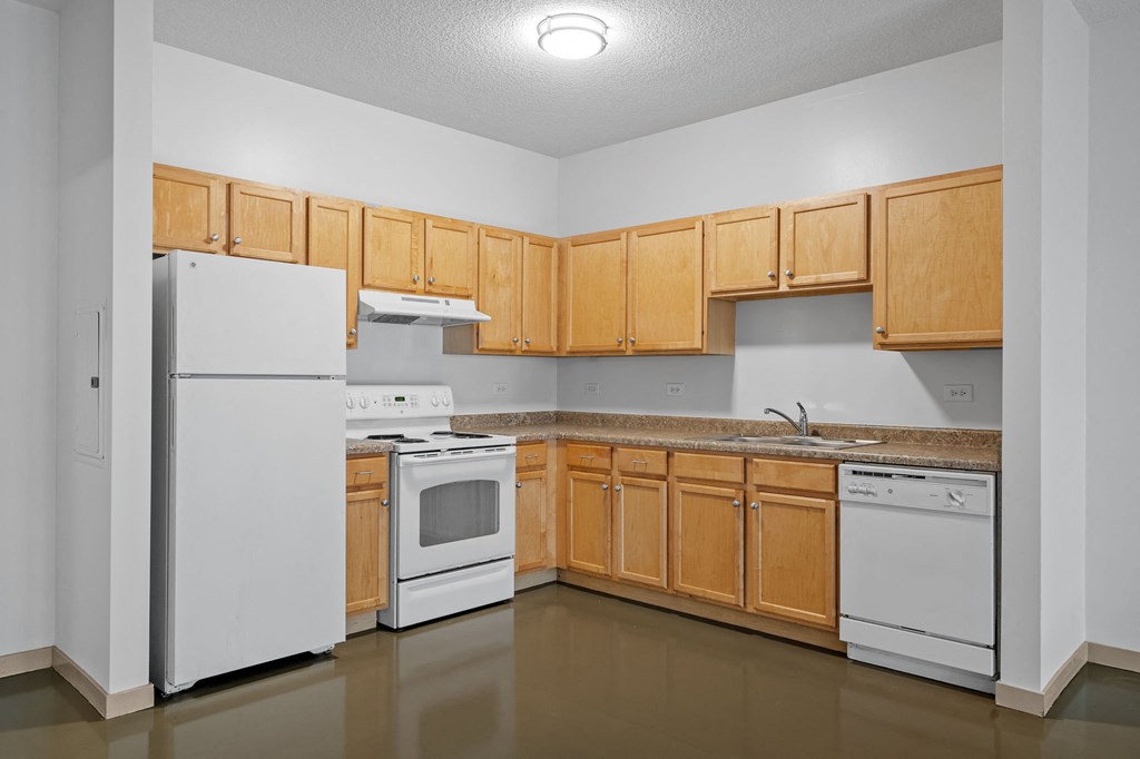 an empty kitchen with white appliances and wood cabinets