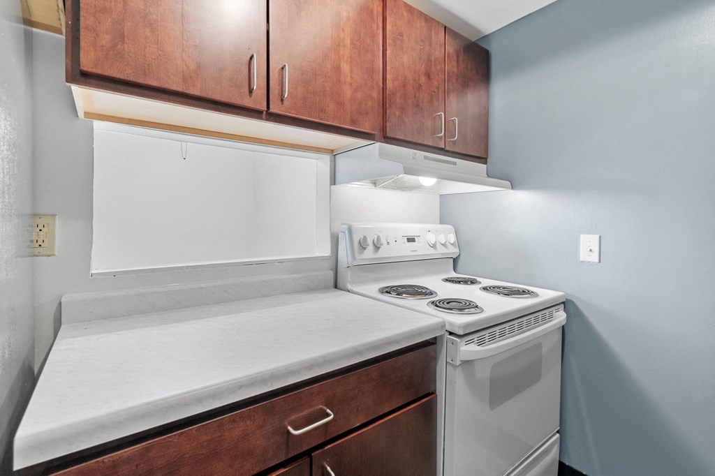 an empty kitchen with white appliances and wooden cabinets