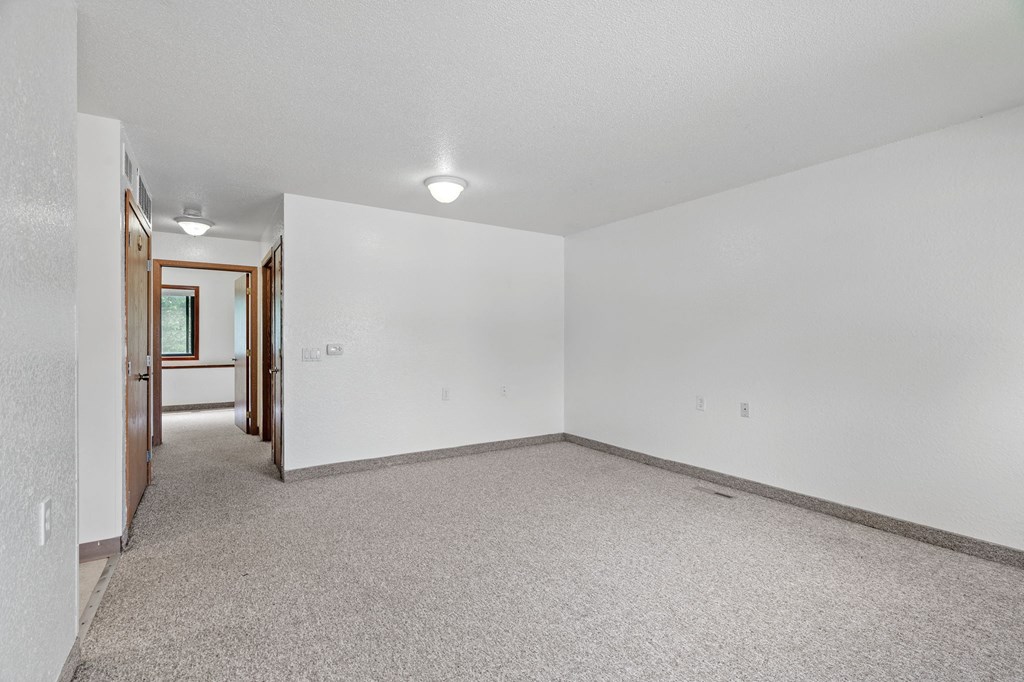 the living room of an empty house with white walls and carpet