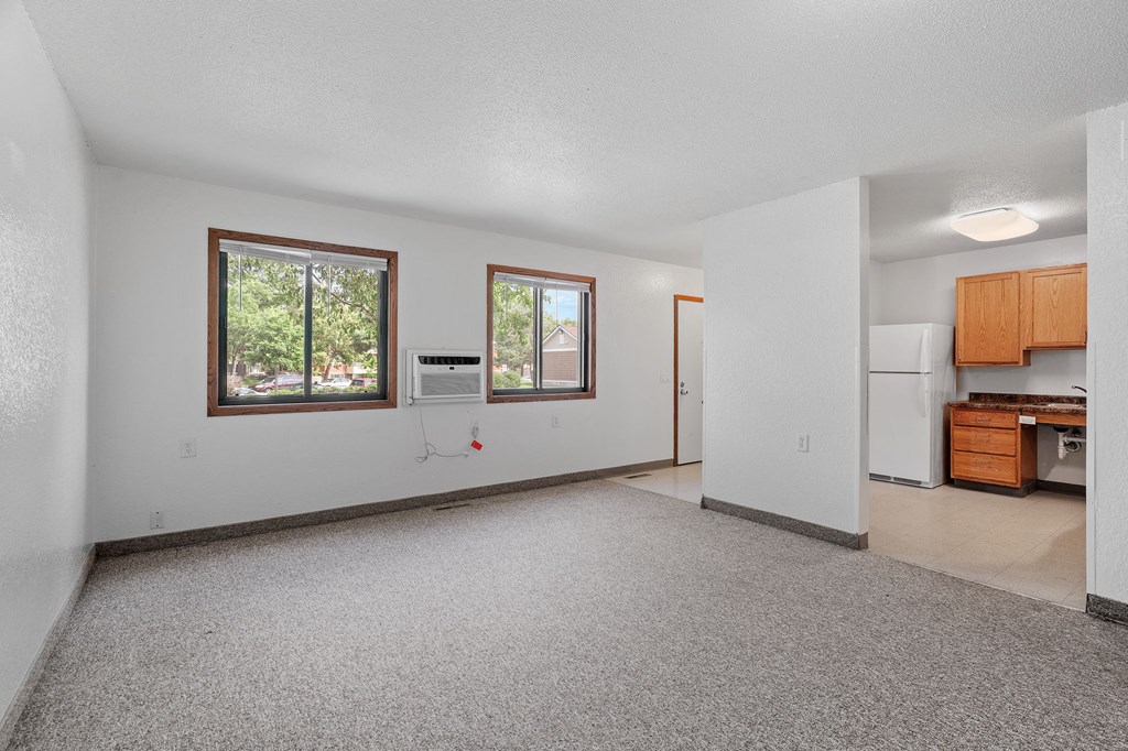 the living room and kitchen of an empty house with a large window