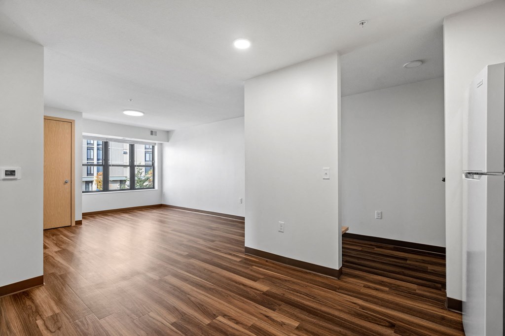 a living room with white walls and wood flooring and a window